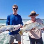 two people holding barramundi