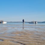 travellers on a shore with tenders